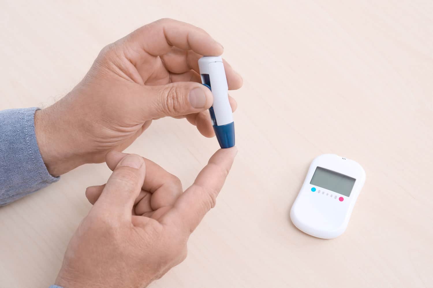 Close-up of a person pricking their fingertip with a lancet to check blood sugar.
