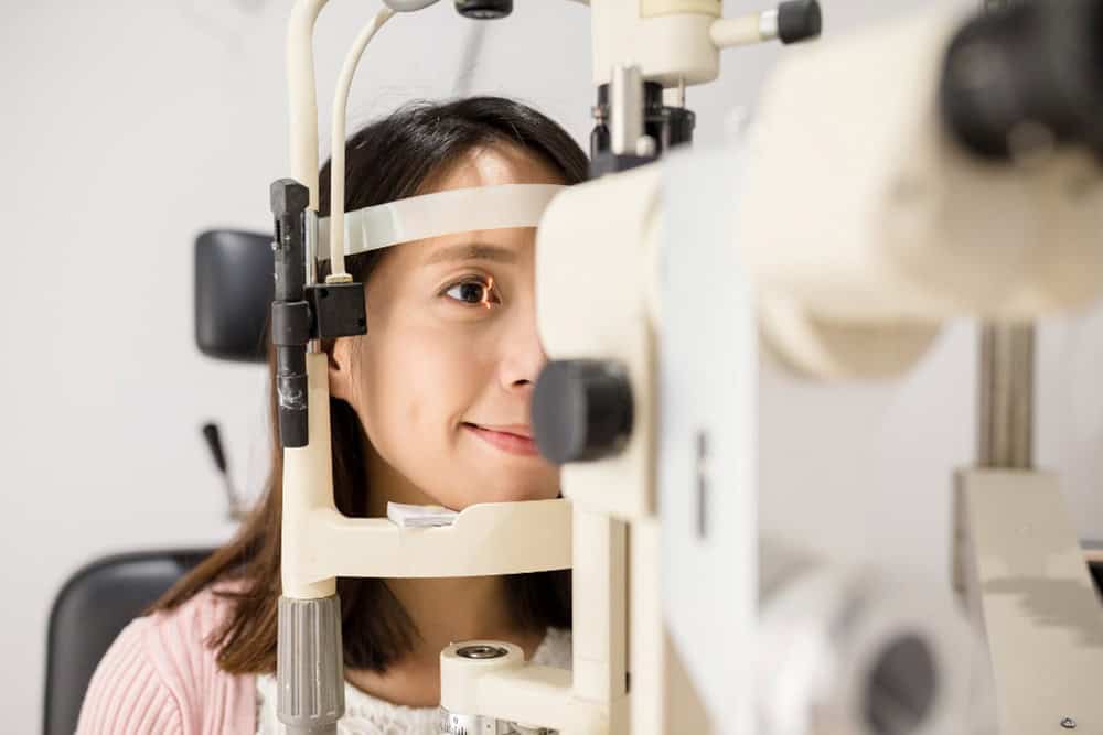 Woman undergoing eye exam with a slit lamp.